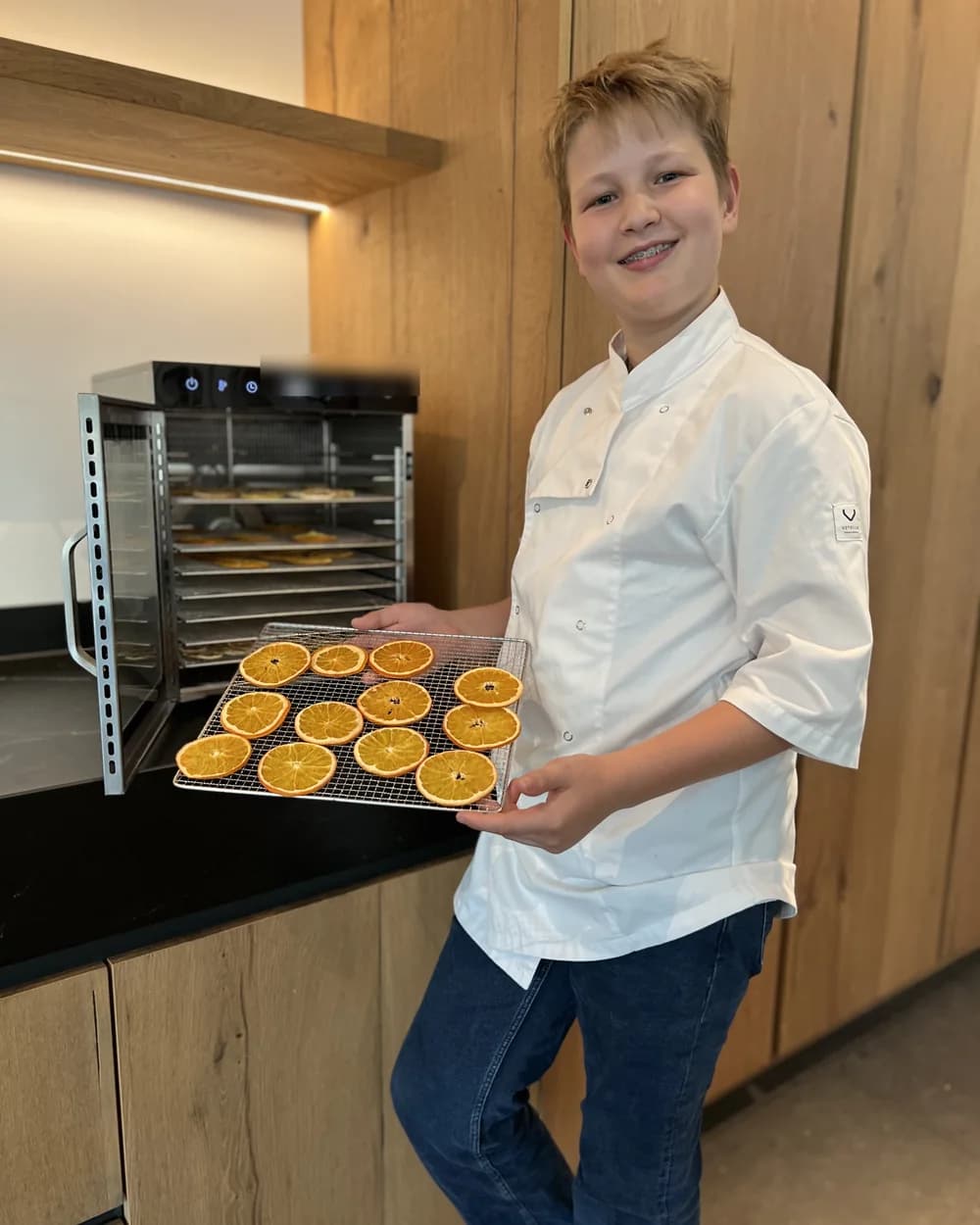 Wessel met een rooster vers gedroogde sinaasappelschijfjes bij zijn droogoven